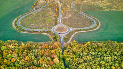 Aerial view on circular road intersection in beautiful autumn forest. Aerial view of round interchange during autumn.