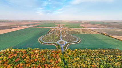 Aerial view on circular road intersection in beautiful autumn forest. Aerial view of round interchange during autumn.