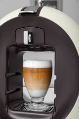 Modern coffee machine with glass of hot latte on white background, closeup