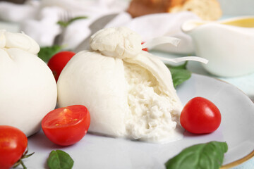 Plate with tasty Burrata cheese on table