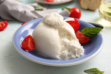 Plate with tasty Burrata cheese on blue background