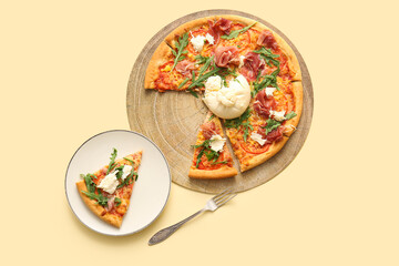 Wooden board and plate of tasty pizza with Burrata cheese on yellow background