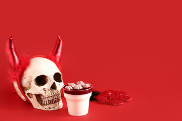 Delicious panna cotta, skull and Halloween accessories on red background