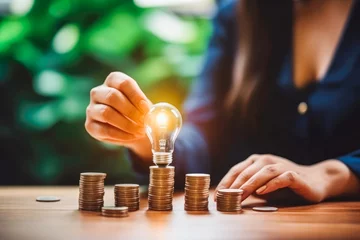 Foto op Plexiglas Close up of business woman putting light bulb on piles of coins, concept of business idea © VisualProduction
