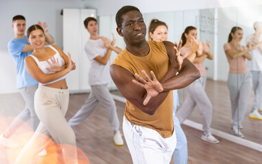 Group of energetic different people learning dance at dance class