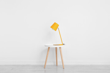 Desk lamp on small table near white wall