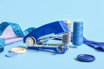 Manual sewing machine with different supplies on blue background © Pixel-Shot