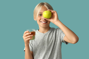 Little boy with glass of juice and apple on blue background