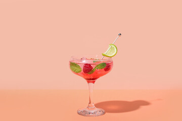 Glass of fresh raspberry mojito on colorful background