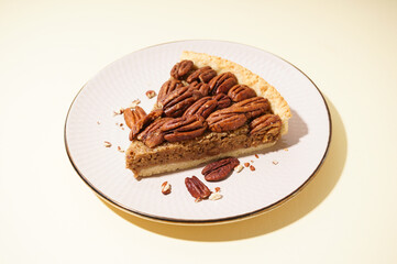 Plate with piece of tasty pecan pie on yellow background