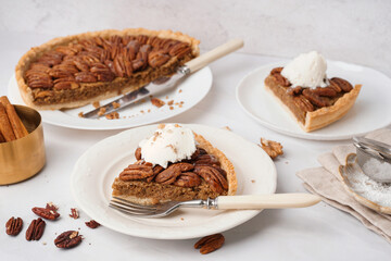 Plates with pieces of tasty pecan pie on white background