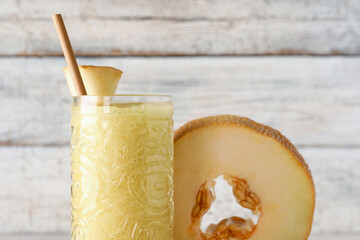Glass of tasty melon smoothie on white wooden background