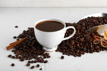 Cup of tasty coffee with cinnamon and beans on white background