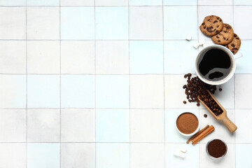 Cup of tasty coffee with cinnamon, beans and cookies on white tile background