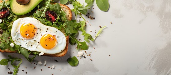Top down view of bread with fried eggs avocado and greens on a light stone background - Powered by Adobe