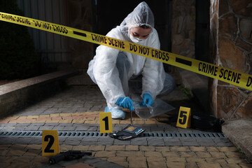 Criminologist working with evidences at crime scene outdoors