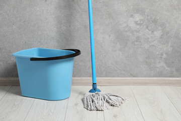 Mop and plastic bucket indoors. Space for text