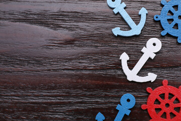 Anchor and ship wheel figures on dark wooden table, flat lay. Space for text