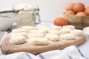Fototapeta na wymiar Making lazy dumplings. Wooden board with cut dough and flour on table, closeup