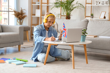 Mature woman in headphones learning English language online at home