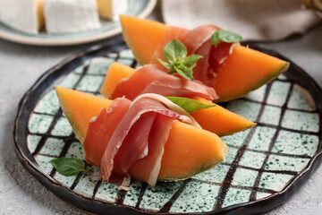 Plate with tasty melon and prosciutto on grunge background, closeup