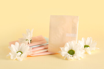 Stack of menstrual pads and chamomile flowers on color background