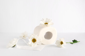 Fototapeta na wymiar Toilet paper roll with chamomile flowers on white background