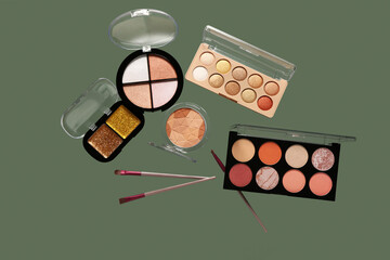 Beautiful palettes of eyeshadows and brushes on green background
