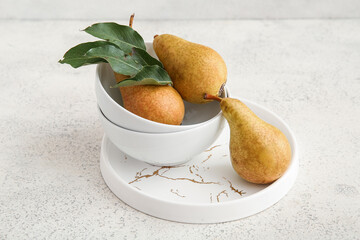 Bowls with ripe pears on white background