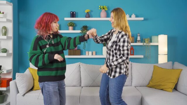 Friends dance funny and witty together at home.