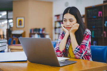 Students feel bored and stressed after working on their laptops and looking for books to study, make reports, find useful information in the university room.