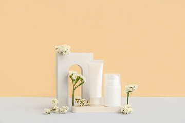 Composition with different cosmetic products, plaster podium and beautiful flowers on beige background