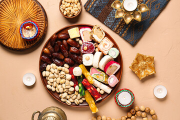 Diya lamps, candles, beads and plates of different treats on beige background. Divaly celebration