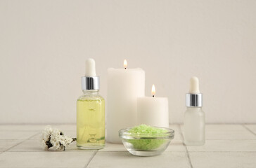 Fototapeta na wymiar Bottles of essential oil, candles and sea salt on table