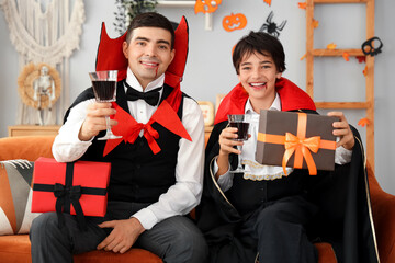 Little boy and his father dressed for Halloween as vampires with gifts at home
