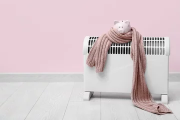Zelfklevend Fotobehang Electric convector heater, piggy bank and scarf near pink wall. Heating season © Pixel-Shot