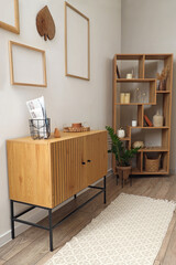 Interior of light living room with commode and shelf unit