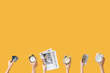 Hands holding different alarm clocks, money, credit cards and newspapers on yellow background