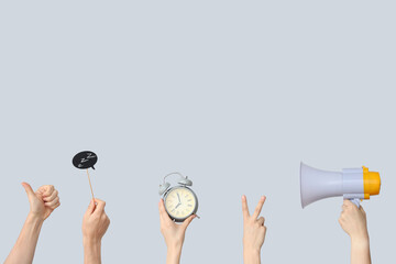 Hands holding alarm clock, megaphone and speech bubble on grey background