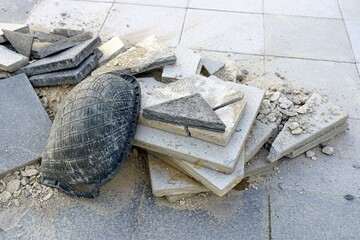 A old black plastic container for scooping sand and stones lay down on the construction scrap.