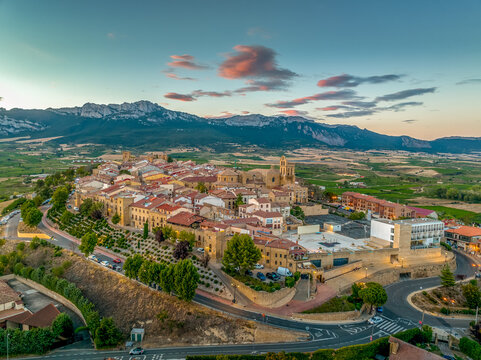 Aerial view of Laguardia medieval fortified hilltop village surrounded by vineries in the Rioja region of Spain, with colorful sunset sky