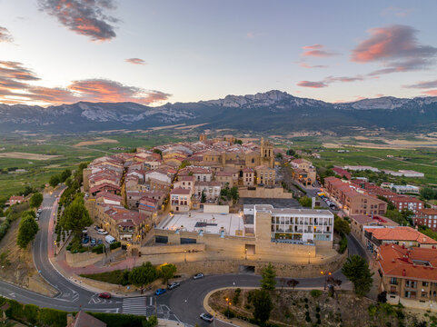 Aerial view of Laguardia medieval fortified hilltop village surrounded by vineries in the Rioja region of Spain, with colorful sunset sky