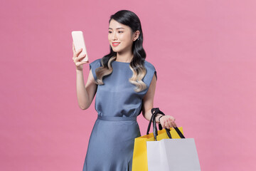 young woman in a blue dress holds shopping bags on a pink background, Black Friday, shopping