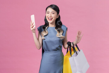 happy young woman holding shopping bags and mobile phone over pink background - obrazy, fototapety, plakaty