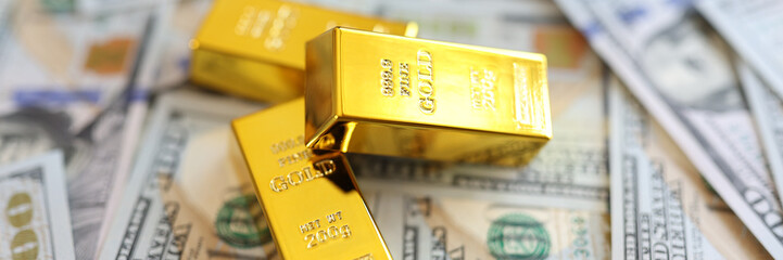 Three gold bullions on background of us dollars banknotes close