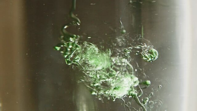Liquid dish soap falling in water in slow motion