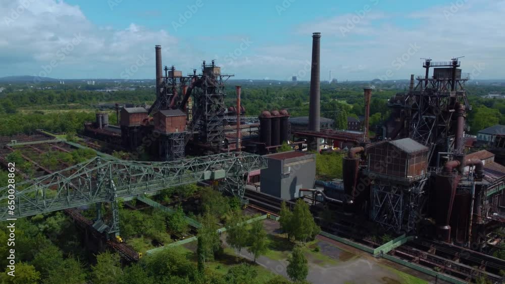Poster rusty aged metal industrial factory in the middle of forest with multiple sections smokestacks tubes