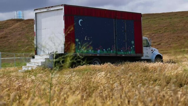 Abandoned truck in a field with spray painted night sky on the side 