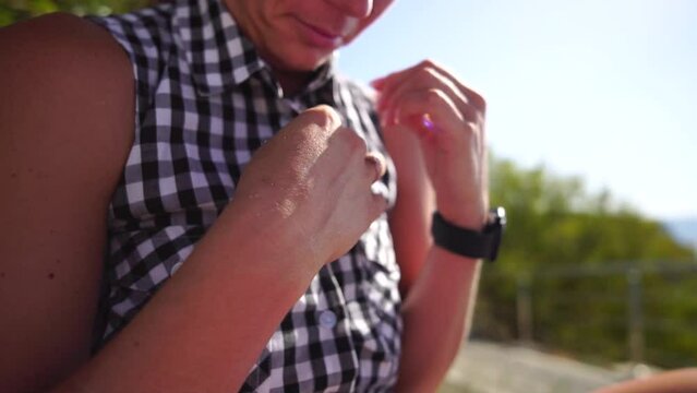 Young happy woman unbuttoning plaid shirt. Side view on female body part in plaid blouse. Close up of unrecognizable woman unbutton her blouse outside in park. Summer Vacation in hot weather concept