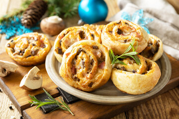 Pizza rolls puff pastry stuffed with prosciutto bacon, mushrooms and cheese on the Christmas table, italian appetizers.